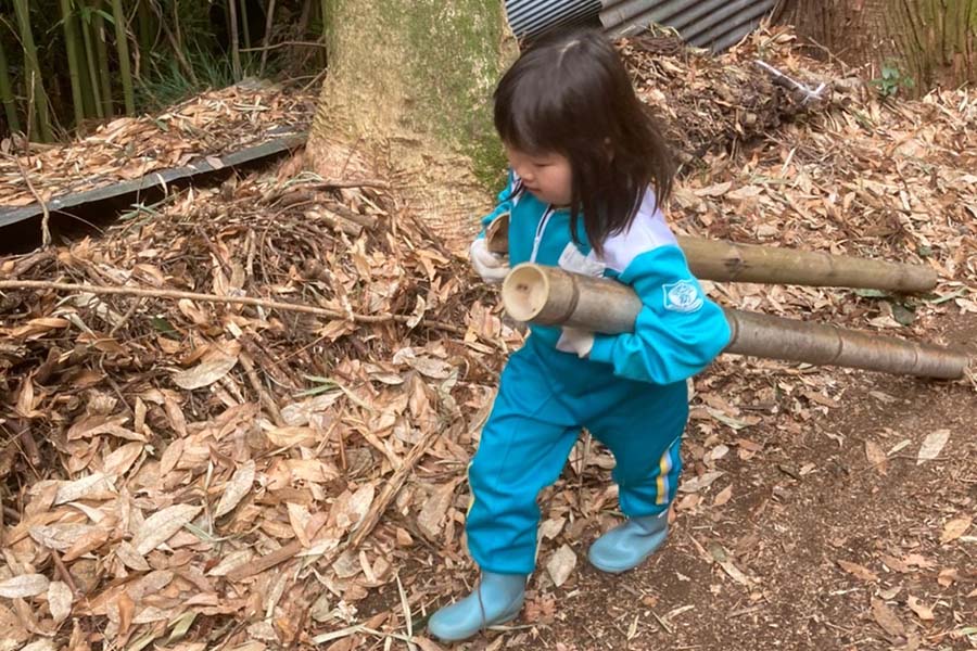 小さい女の子が竹を両脇に抱えて整備のお手伝いをしている