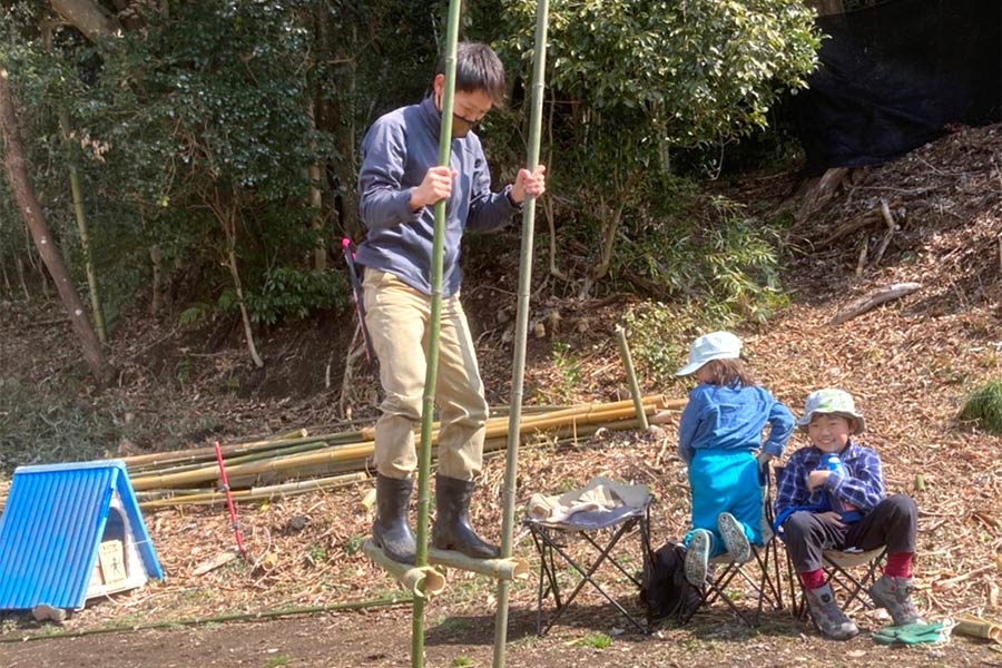 竹馬に乗る男性とそれを横で見る子供二人